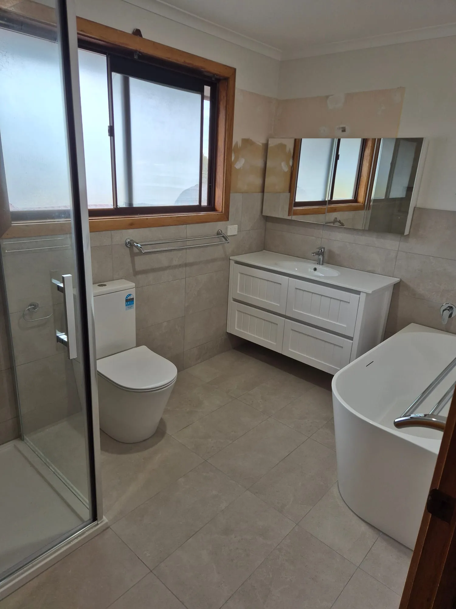 Bathroom with a shower, toilet, shaker vanity and freestanding bath
