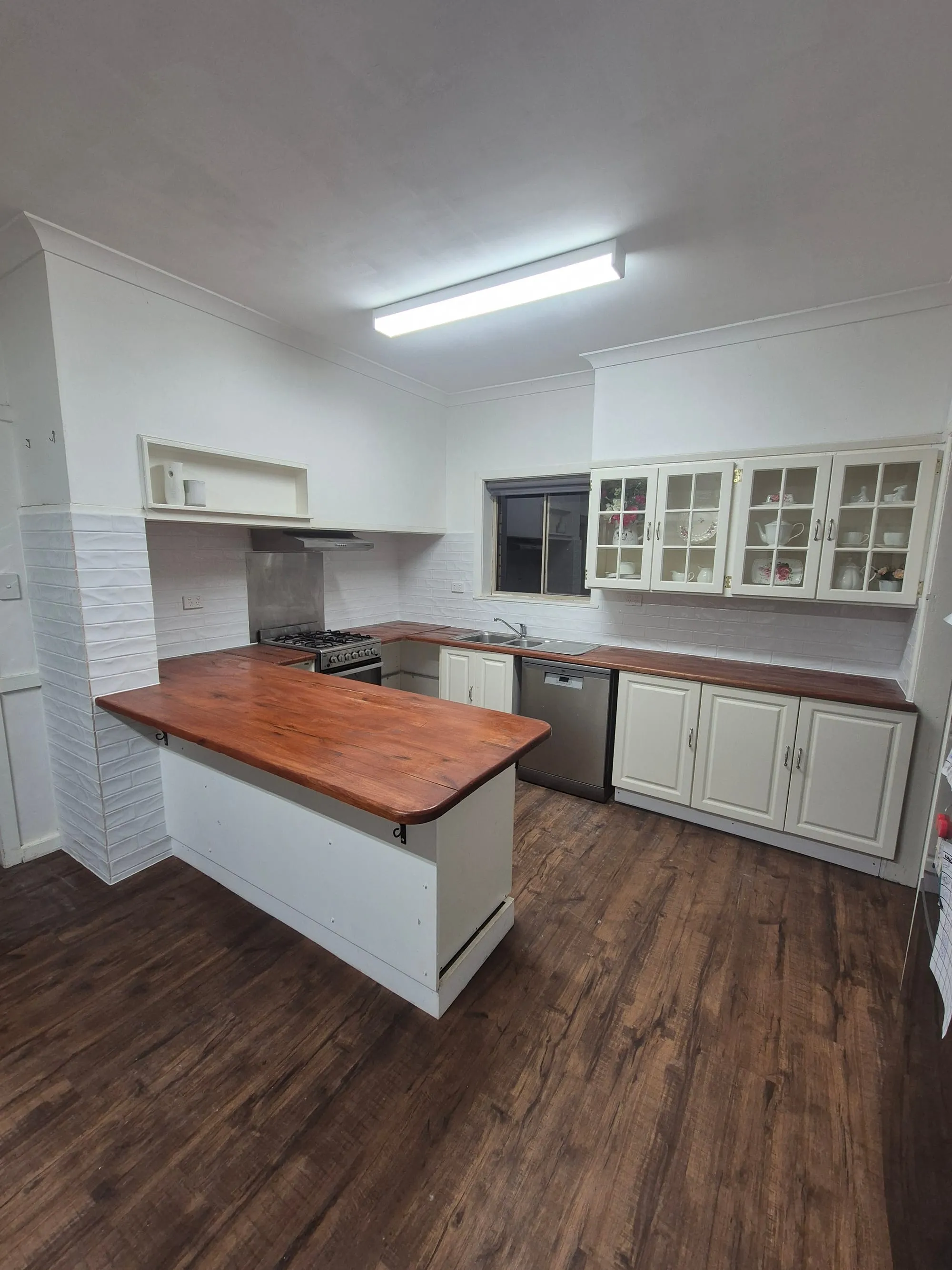 Kitchen with a solid timber benchtop, white cabinetry and glass display cupboards