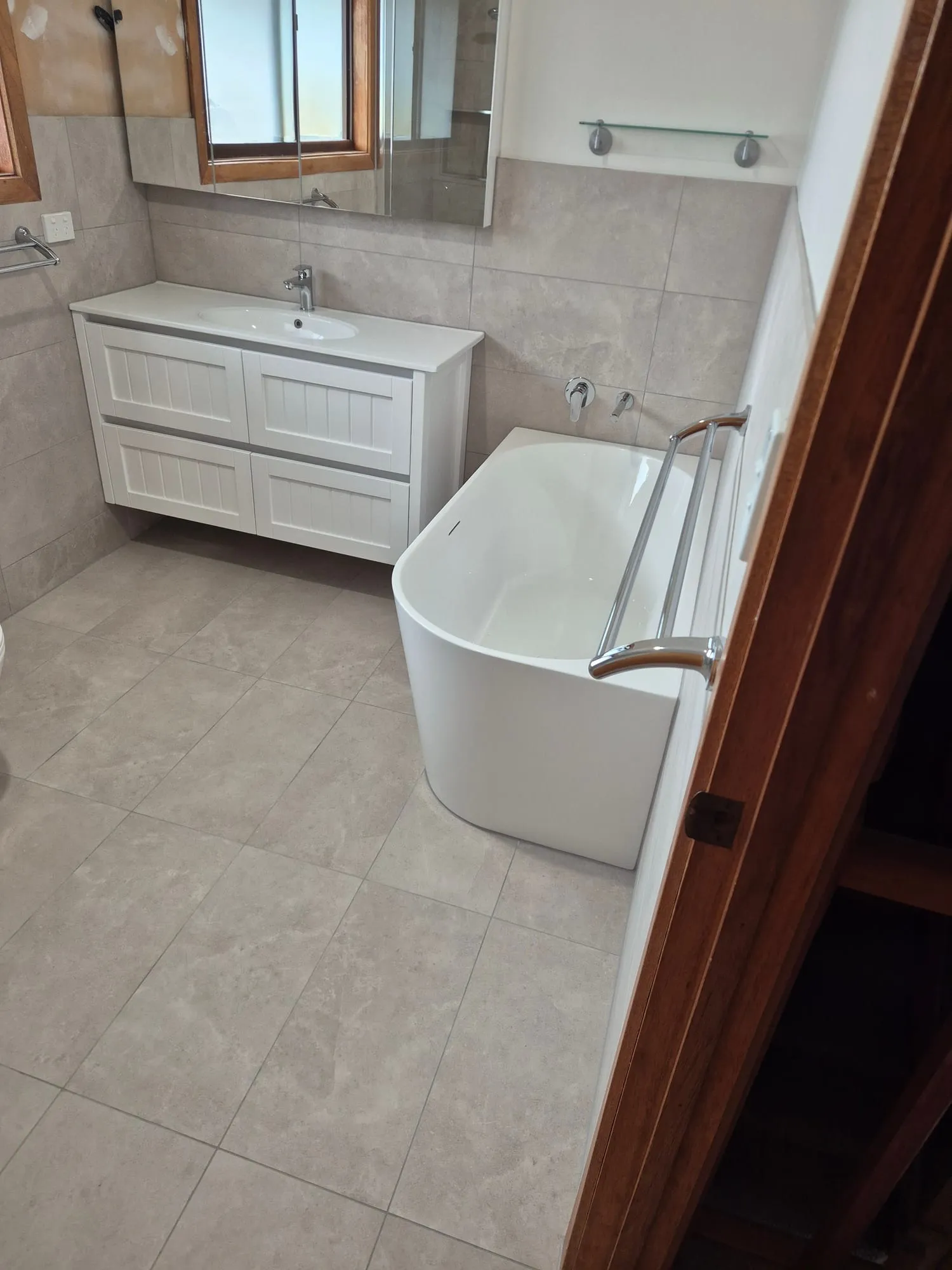 Shaker vanity and mirror beside the freestanding bath
