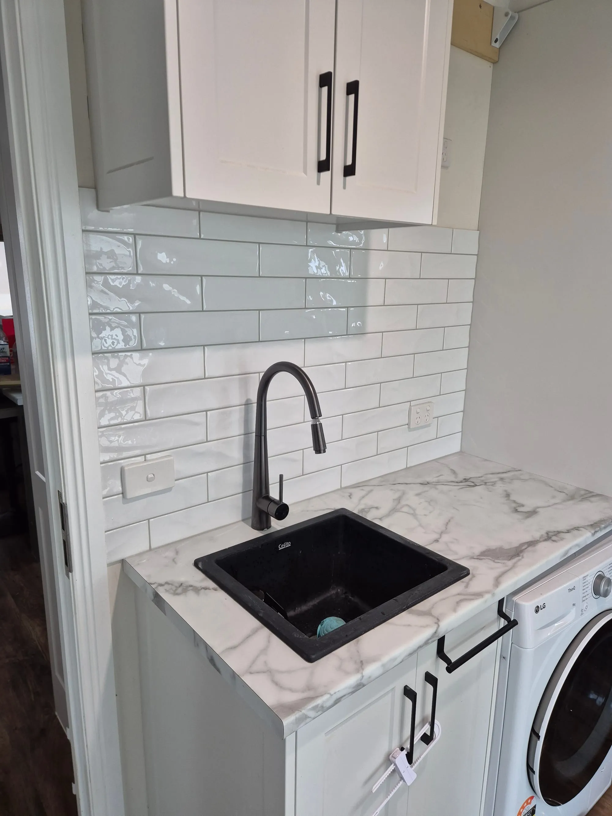 Black sink and black mixer tap against the marble-look splashback