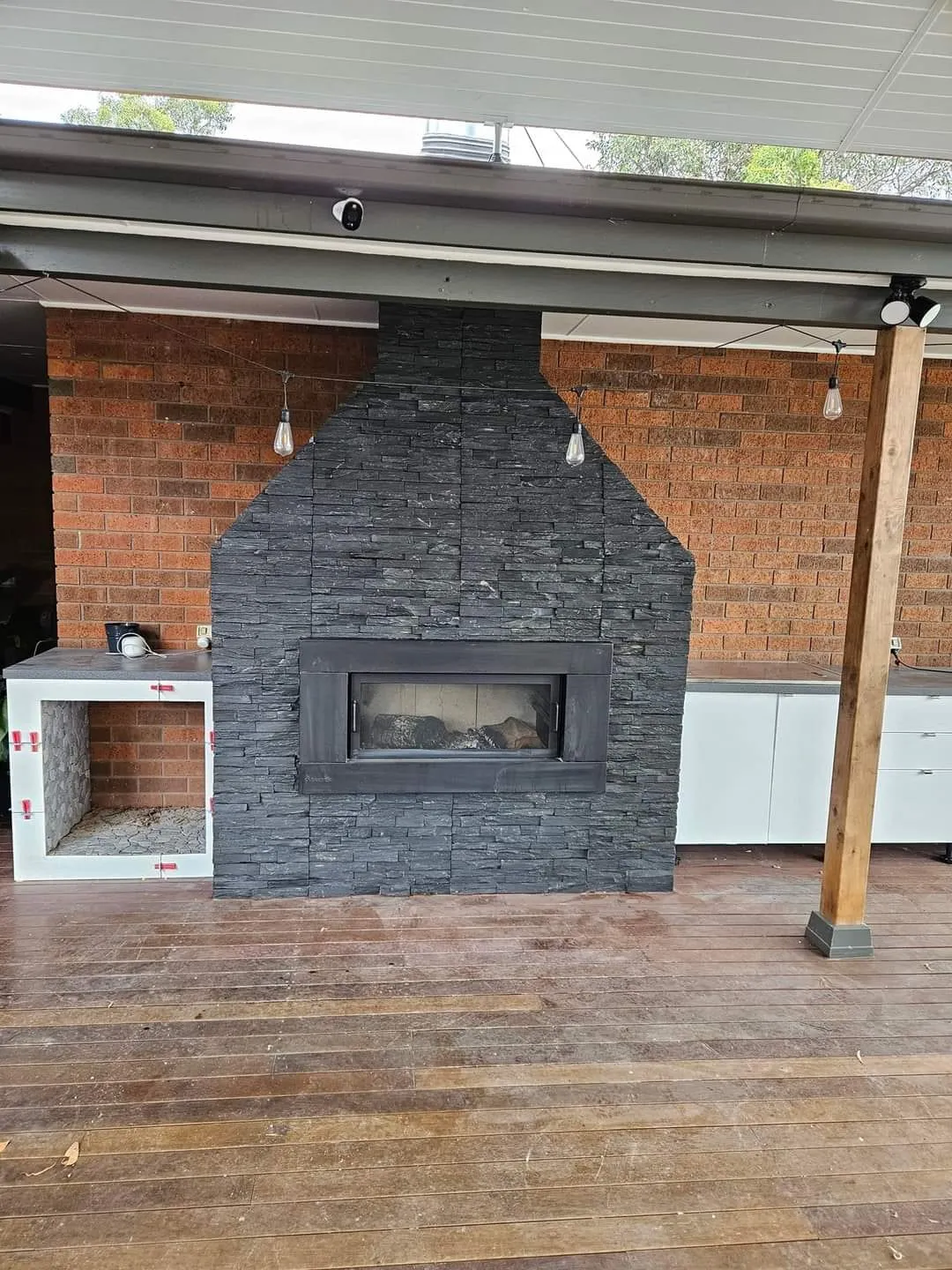 The stacked stone fireplace seen from the deck, against the brick wall