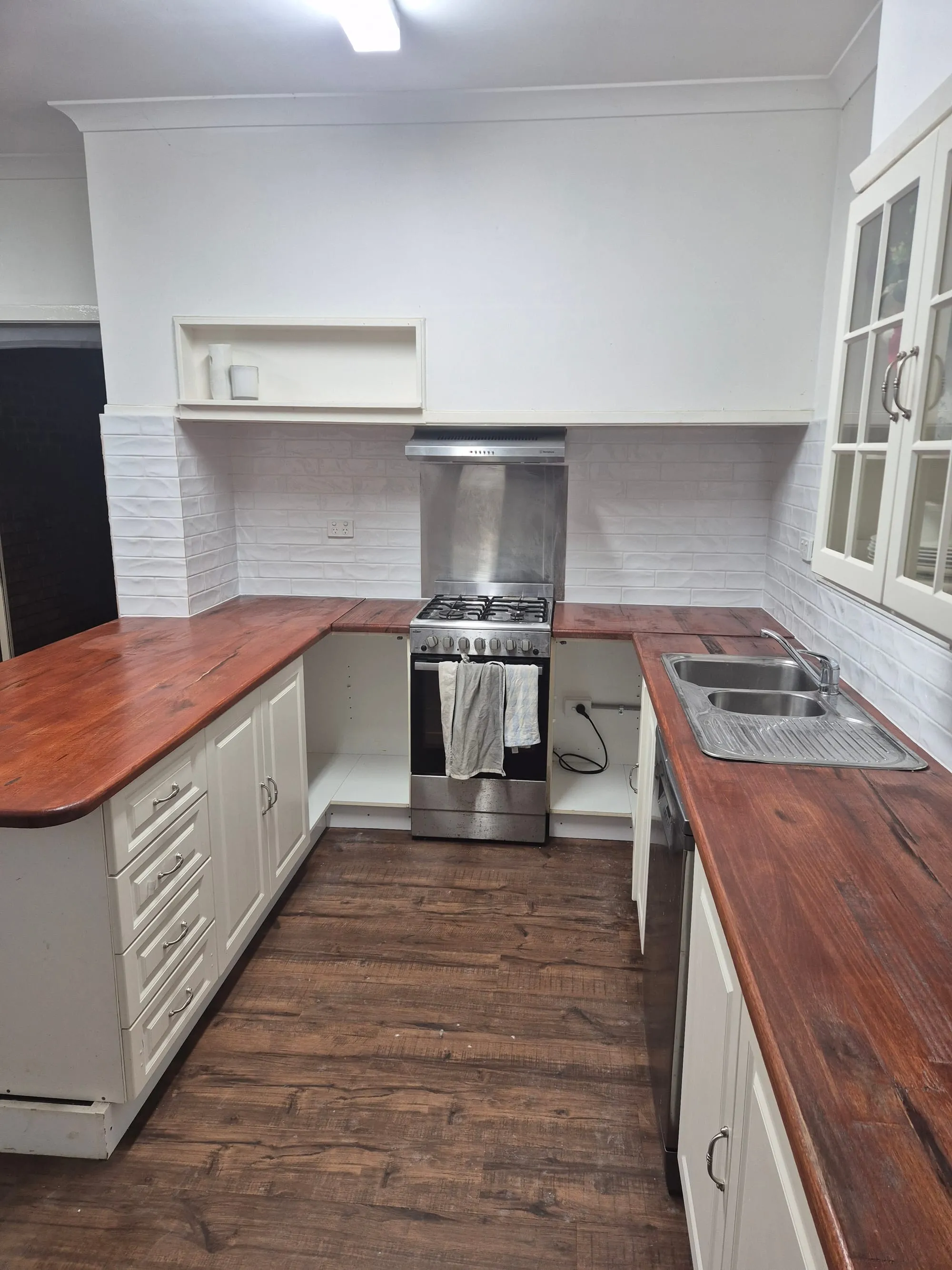 Timber benchtop with the cooktop and rangehood against a subway tile splashback