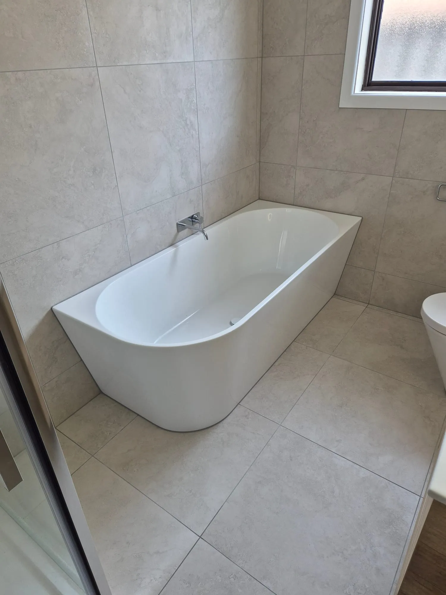 Freestanding bath set against the stone-look wall tile