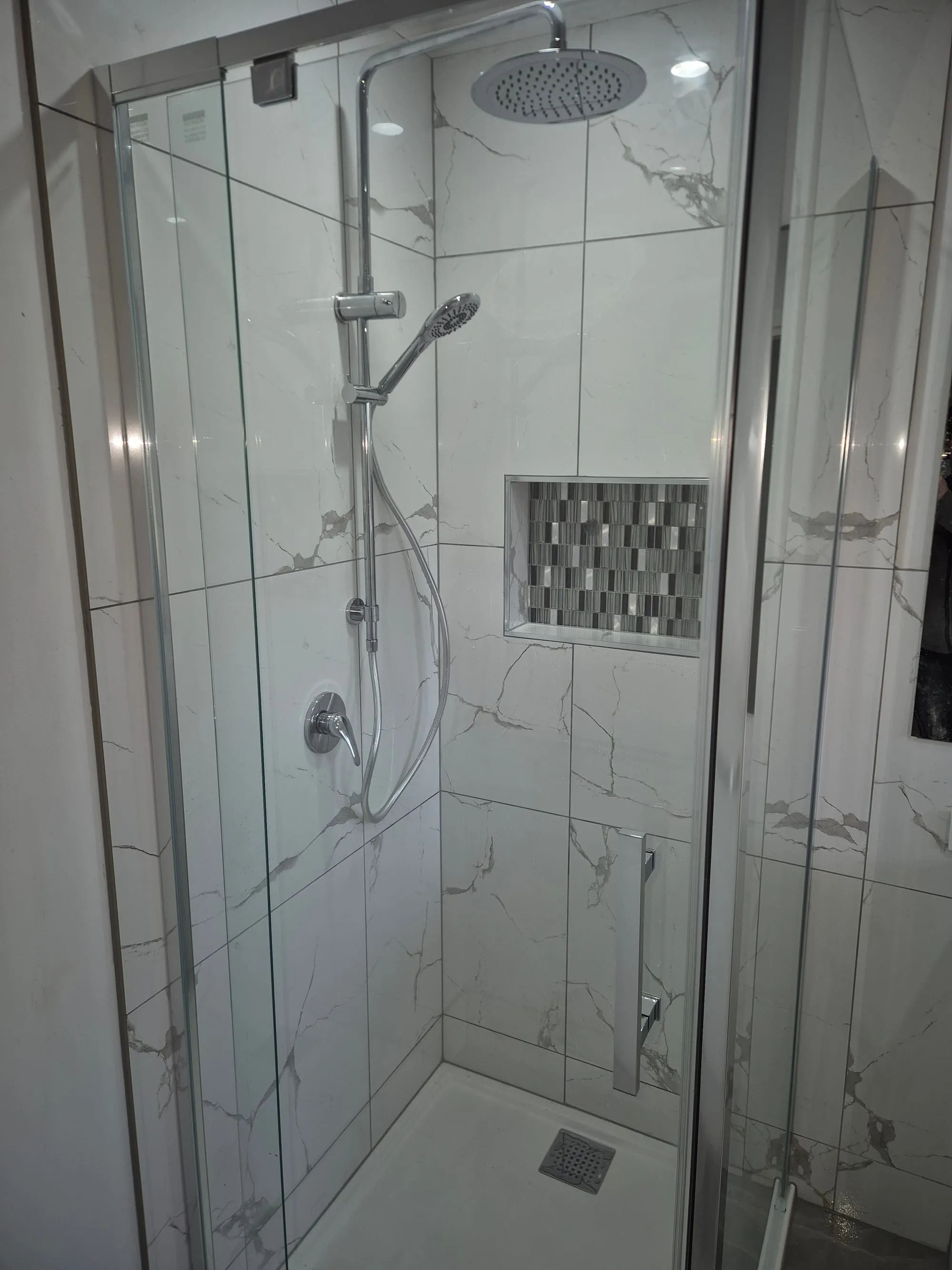Shower with a mosaic feature niche and a hand shower on a rail