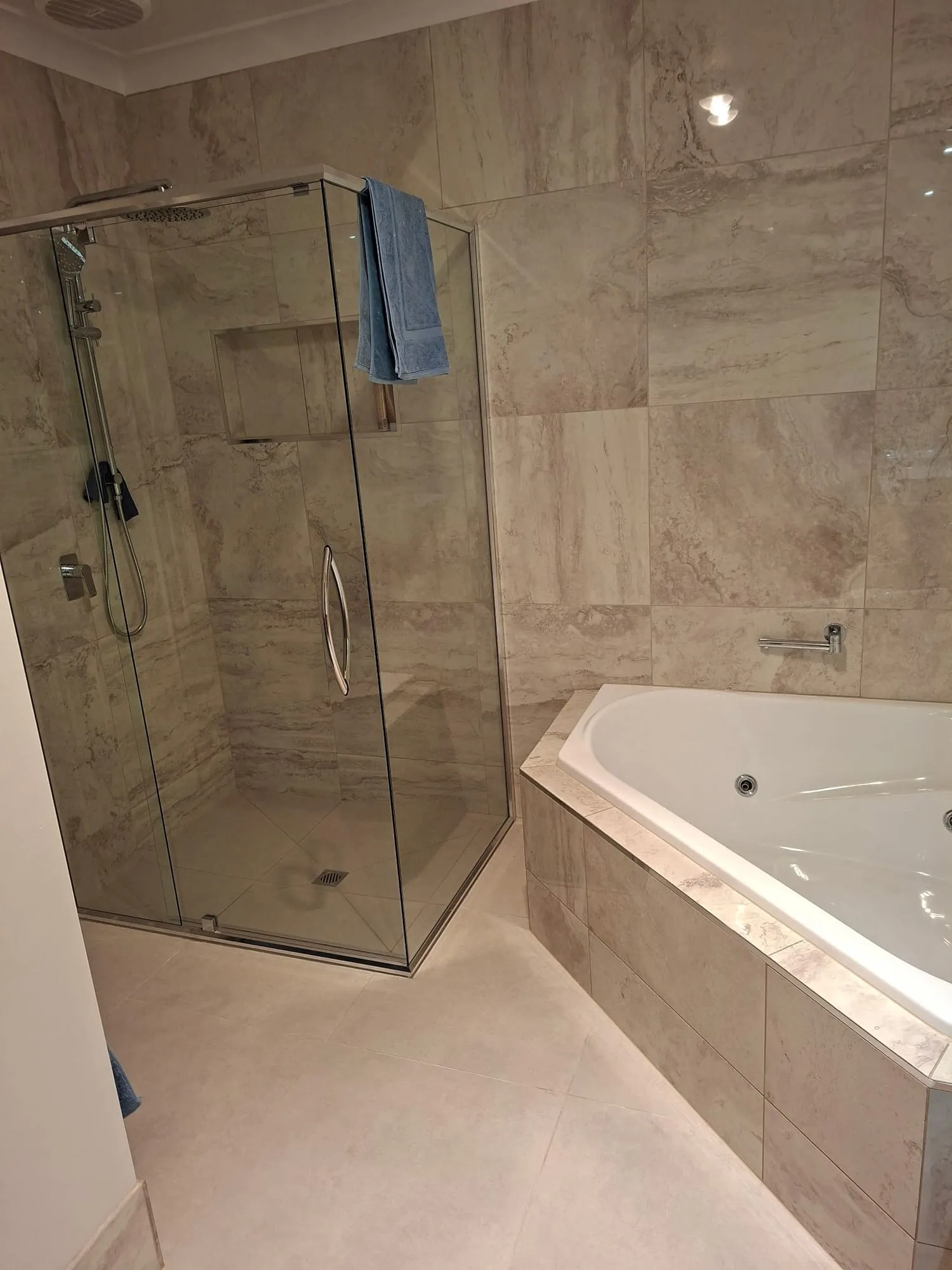 Shower with a glass door, beside the corner spa bath