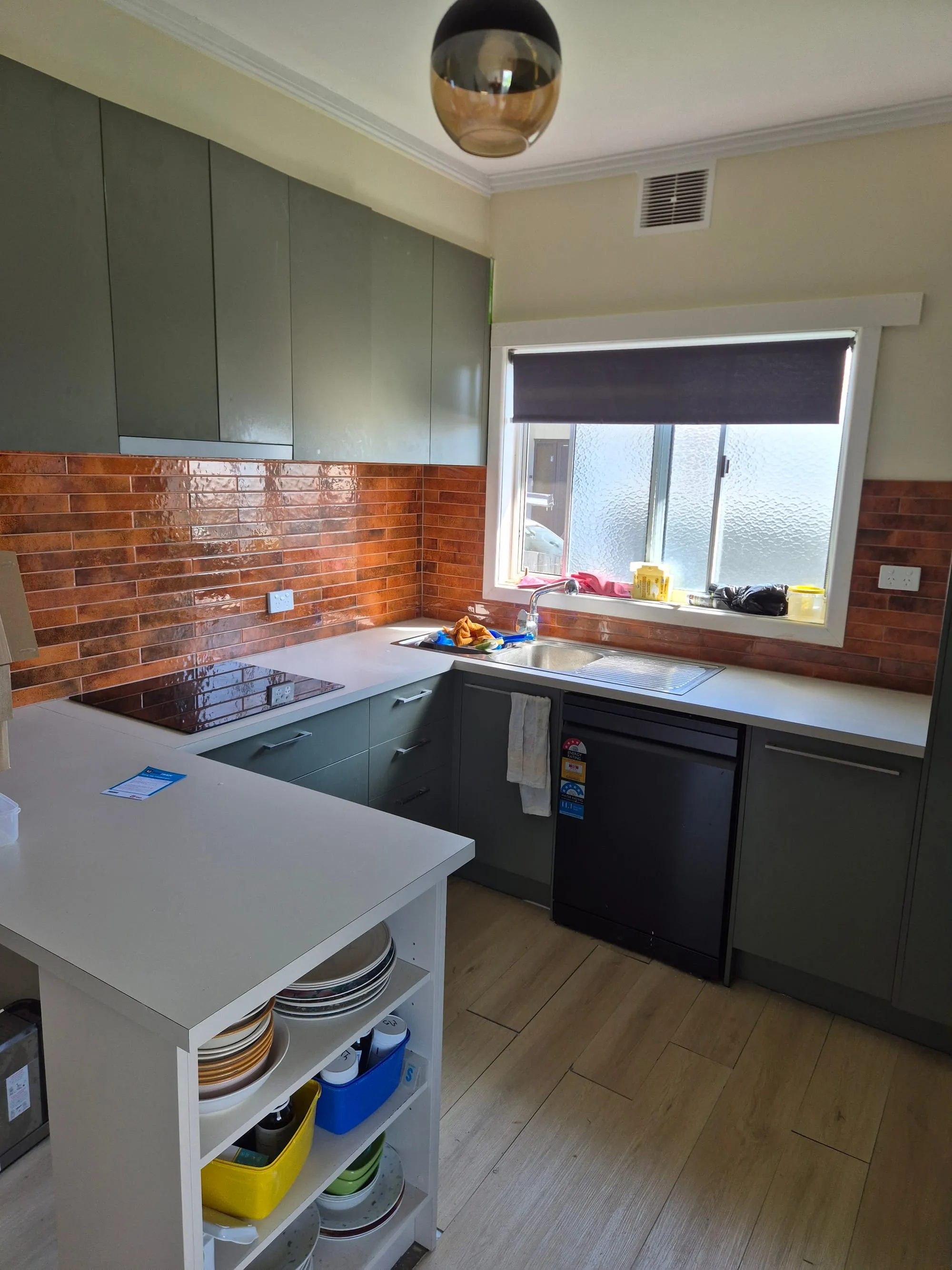Sink and benchtop running to the window, with the brick splashback behind