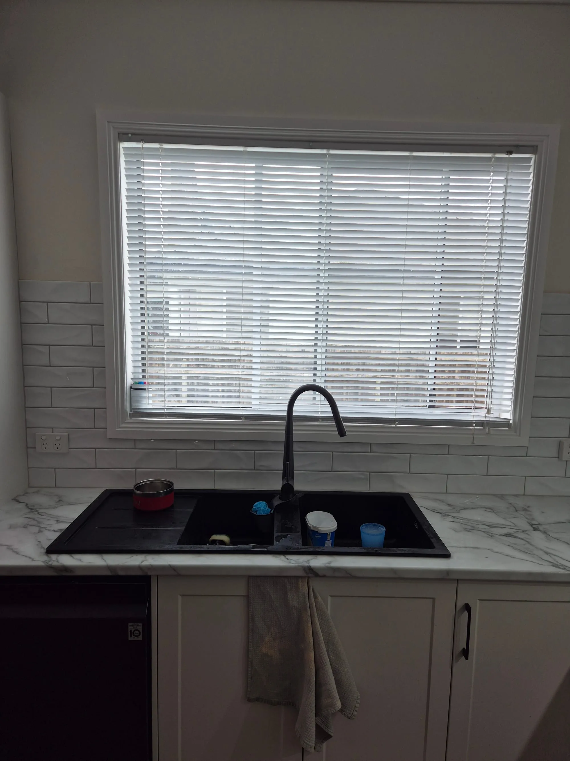 Sink below the window with a black gooseneck tap