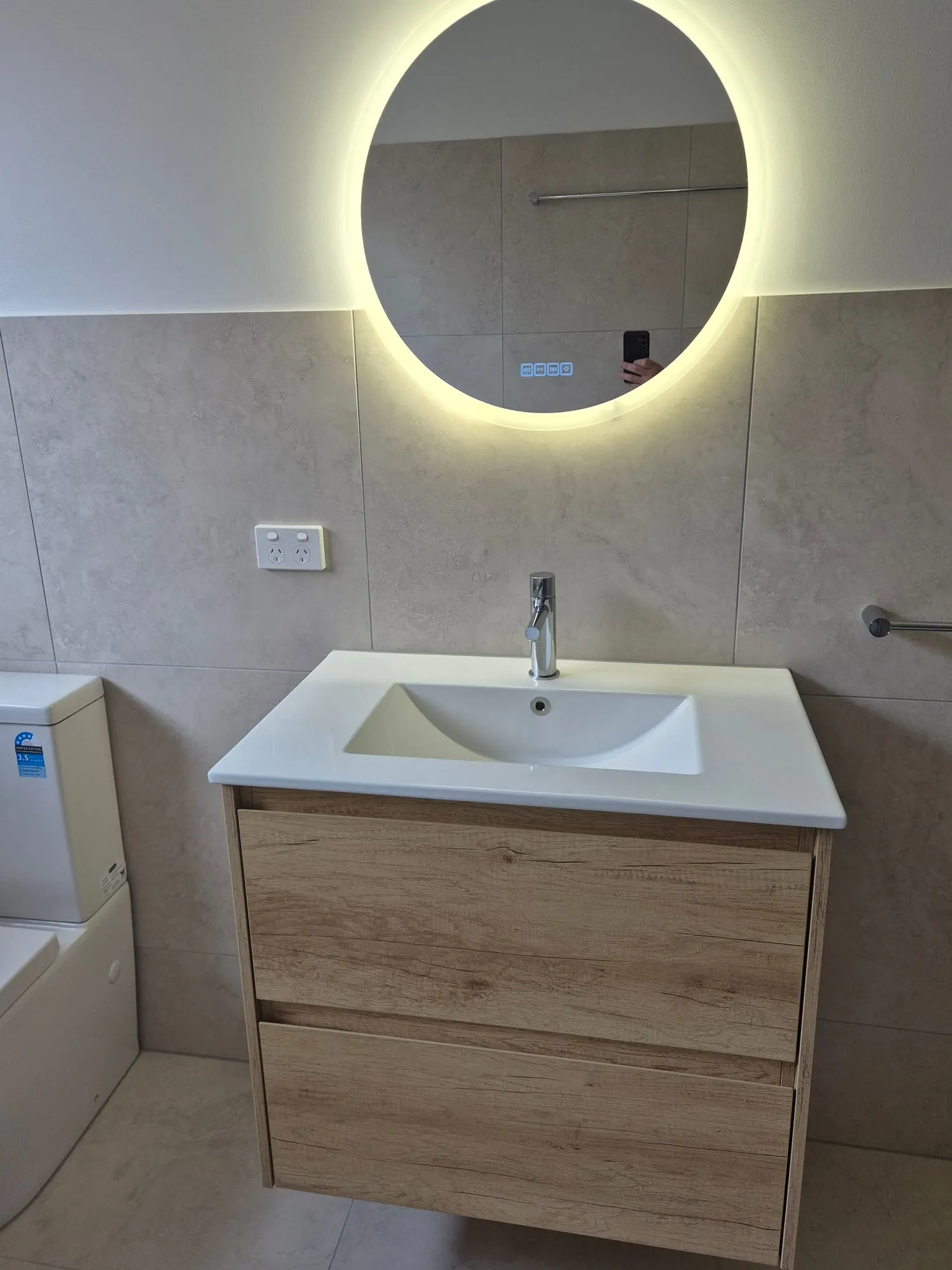 Close view of the timber vanity and basin under the backlit mirror