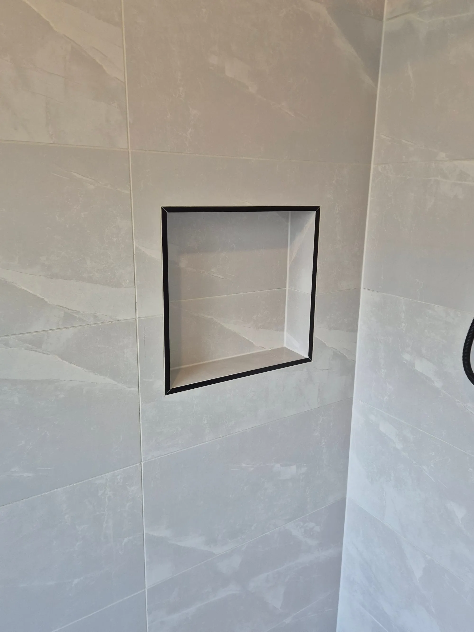 Recessed niche framed in black, set into the wall tile