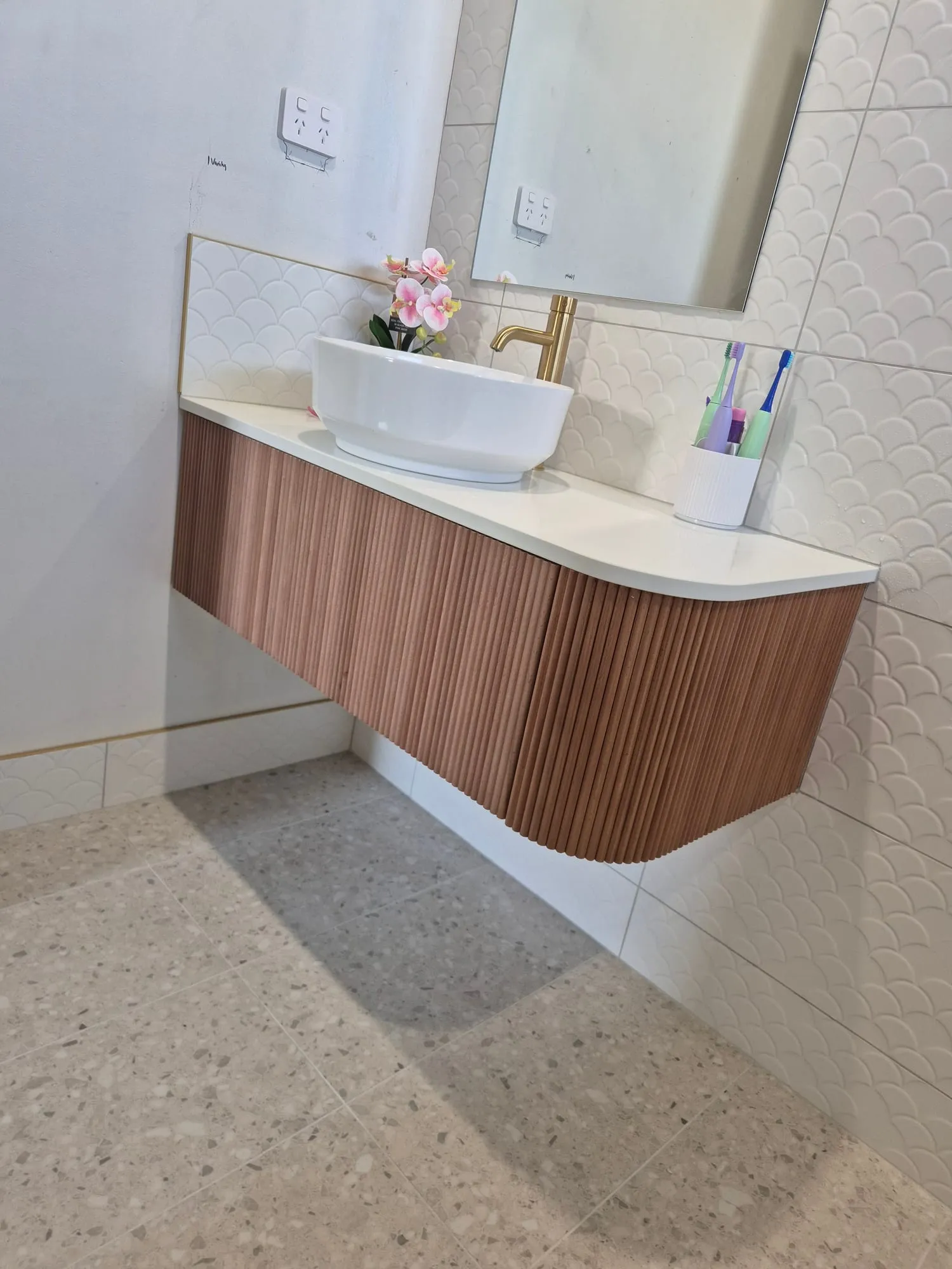 Fluted timber vanity with a vessel basin and brass tapware