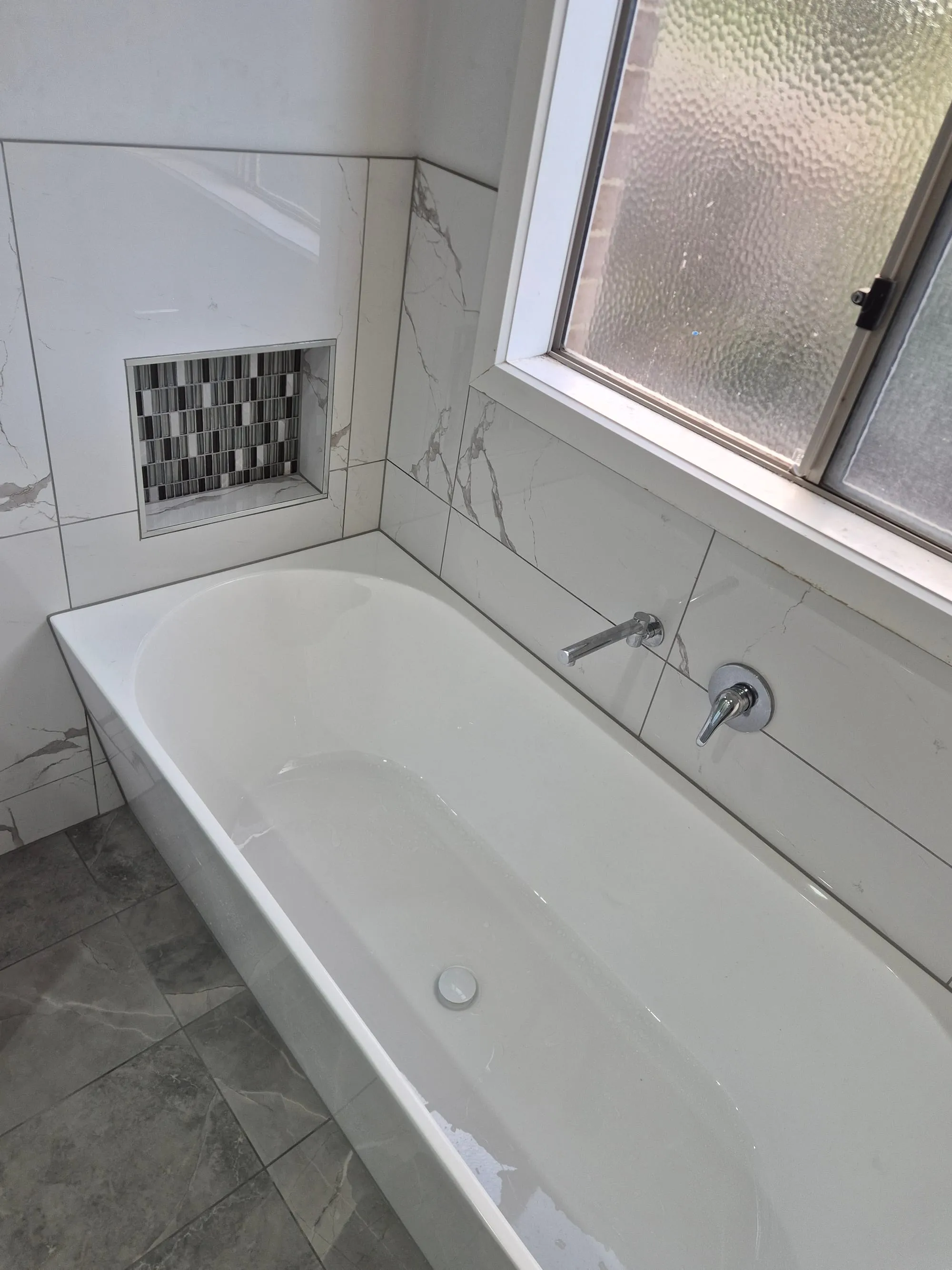 Built-in bath and the tiled surround, seen from the doorway