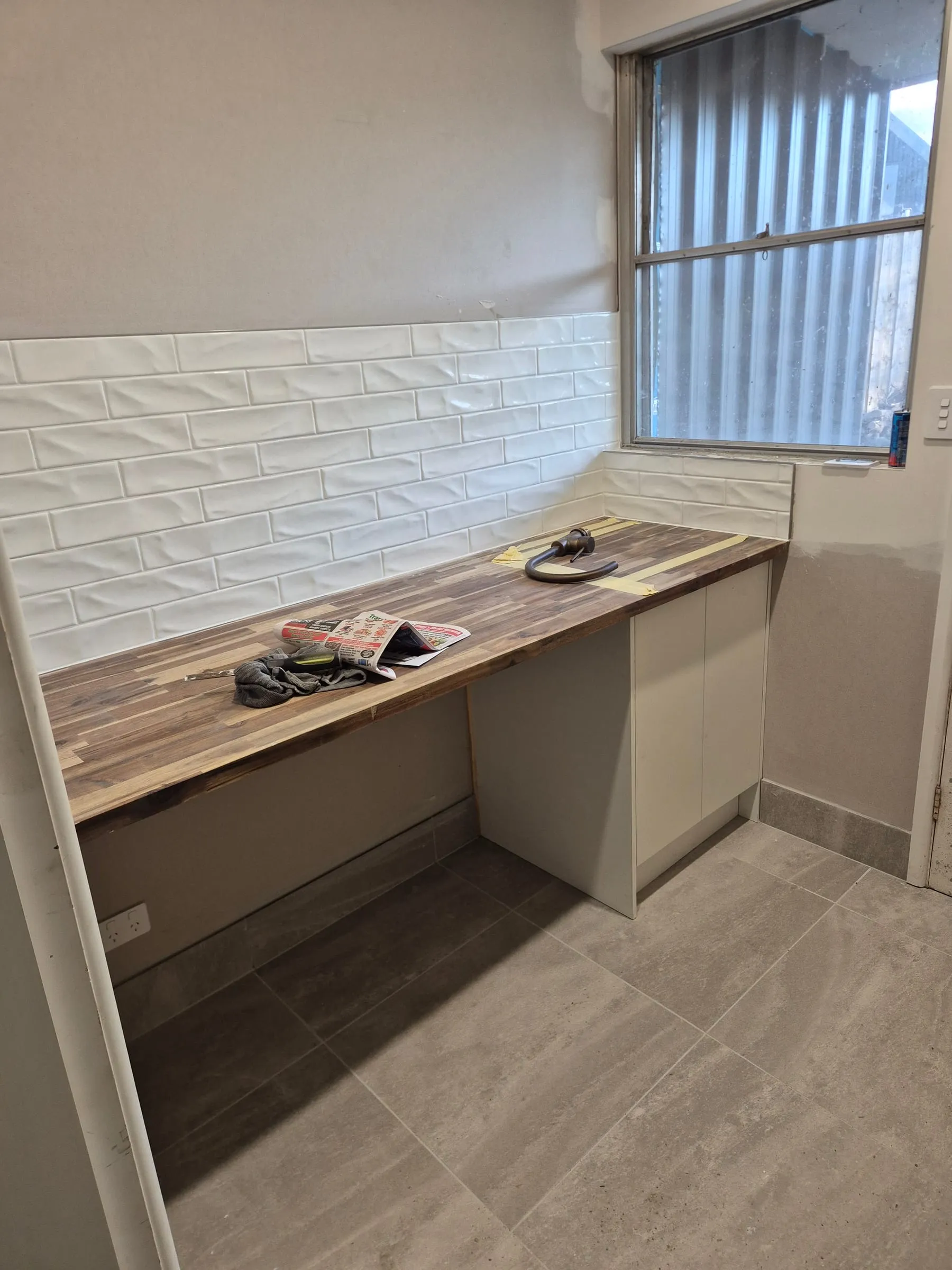 A solid timber benchtop being fitted onto new cabinetry